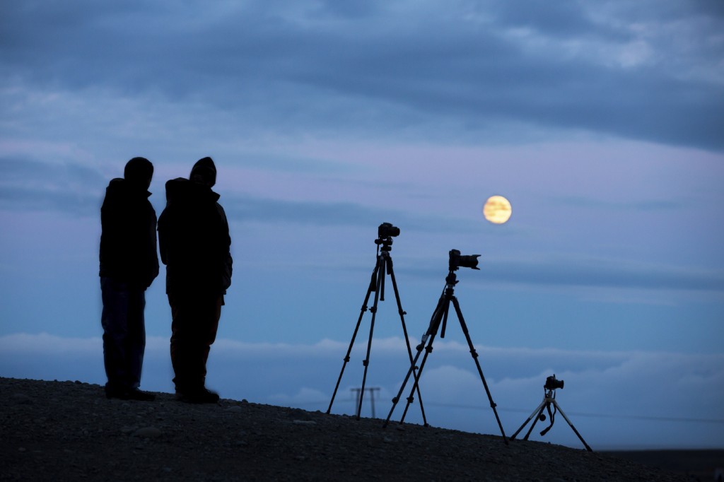 Backlit of photographers with tripod and cameras on full moon