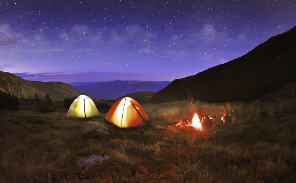 Illuminated yellow camping tent under stars at night